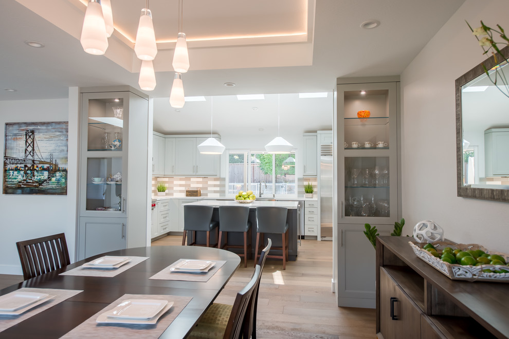 Cette image montre une salle à manger ouverte sur la cuisine minimaliste de taille moyenne avec un mur gris, un sol en bois brun, aucune cheminée et un sol marron.