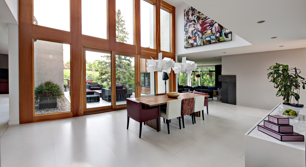 Cette image montre une grande salle à manger ouverte sur la cuisine design avec un mur blanc et sol en béton ciré.