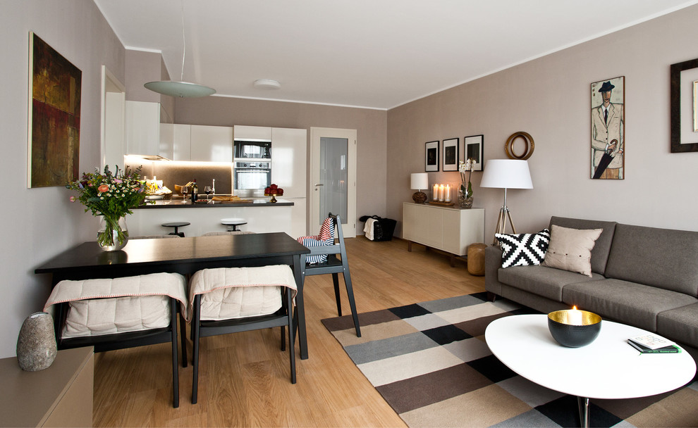 Idee per una sala da pranzo aperta verso il soggiorno minimal di medie dimensioni con pareti beige, pavimento in compensato e nessun camino