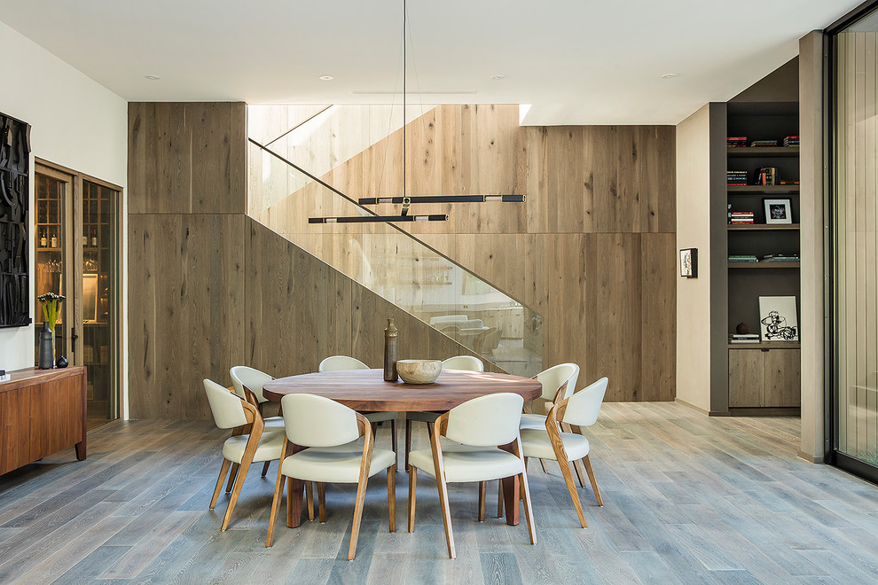 Imagen de comedor moderno con paredes blancas, suelo de madera en tonos medios y suelo marrón