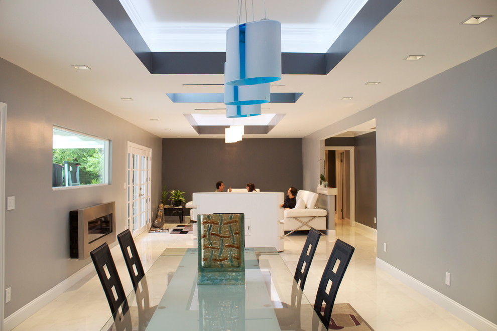 Cette photo montre une grande salle à manger ouverte sur le salon moderne avec un mur bleu, un sol en marbre, une cheminée ribbon et un manteau de cheminée en métal.