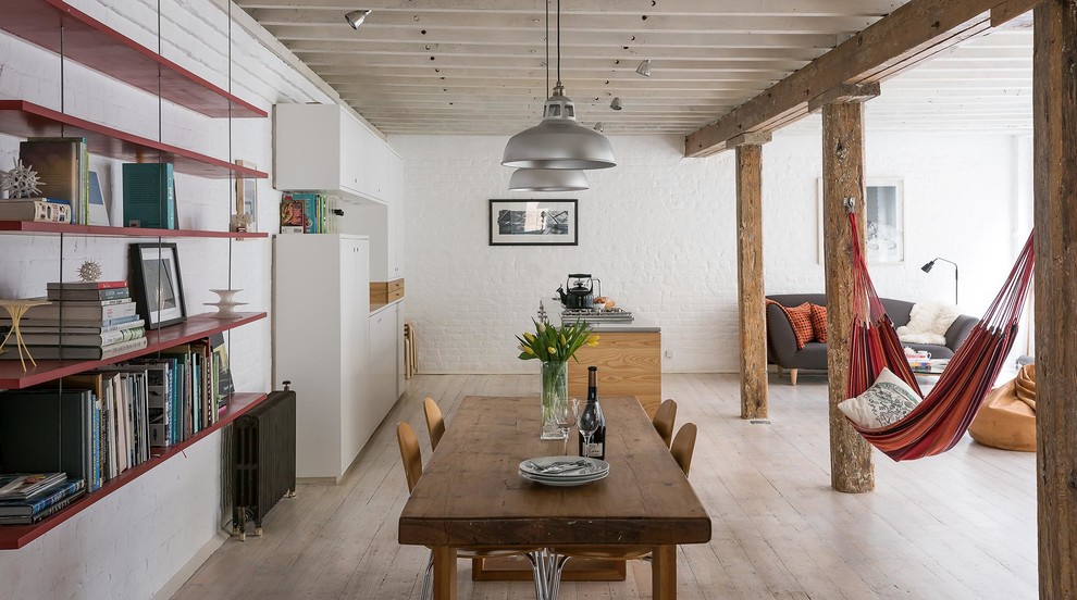 Esempio di una sala da pranzo aperta verso il soggiorno industriale con pareti bianche e parquet chiaro