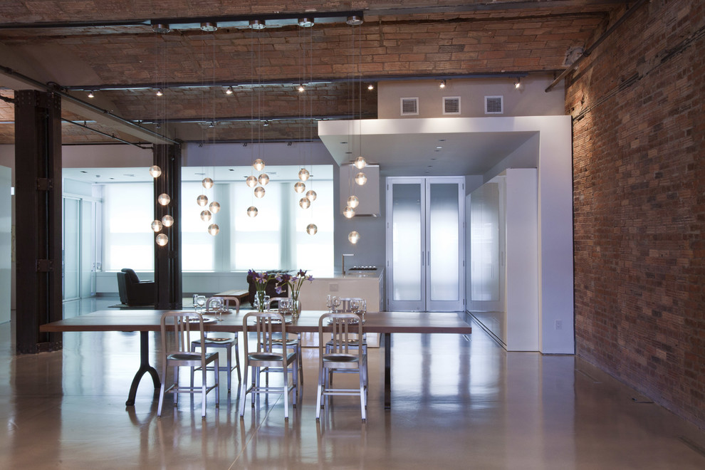 Immagine di una sala da pranzo aperta verso il soggiorno industriale con pavimento in cemento