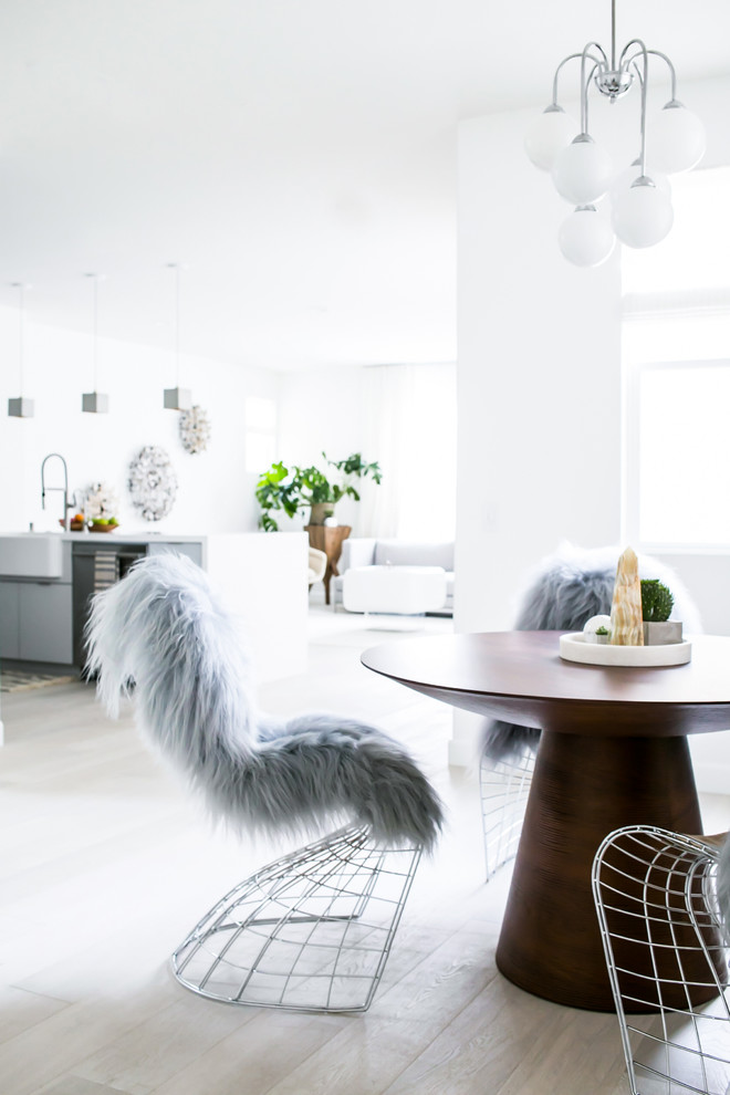 Immagine di una piccola sala da pranzo aperta verso la cucina eclettica con pareti bianche, parquet chiaro e nessun camino
