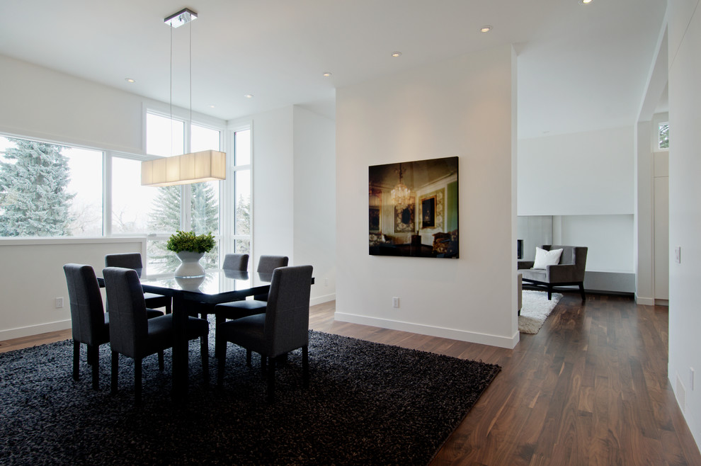 This is an example of a contemporary dining room in Calgary with white walls and medium hardwood flooring.