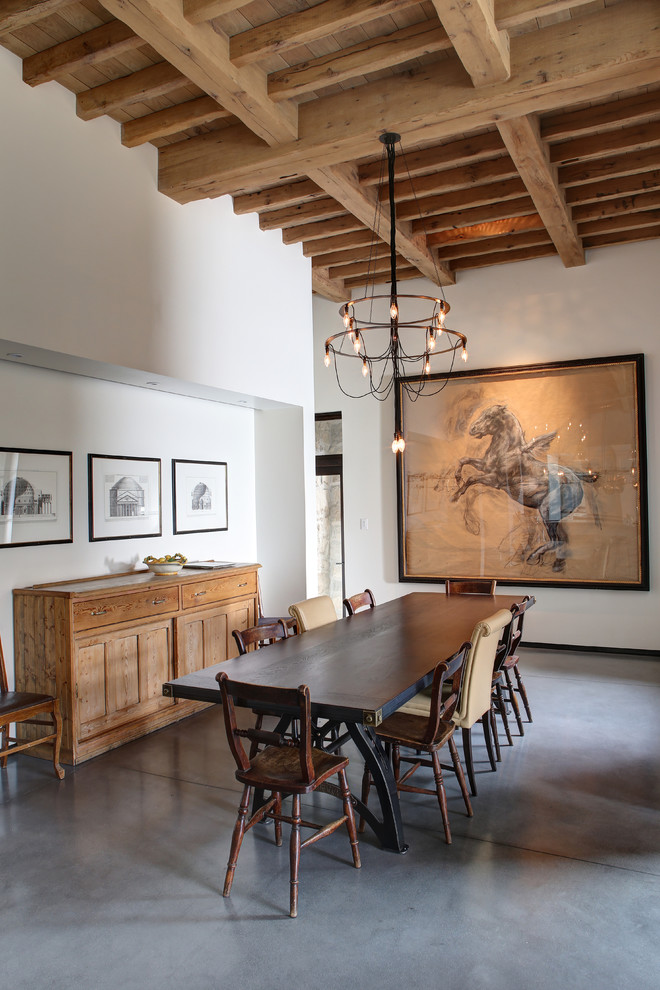 Immagine di una sala da pranzo mediterranea con pareti bianche e pavimento in cemento