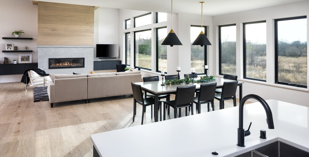 На фото: большая кухня-столовая в стиле модернизм с белыми стенами, стандартным камином, фасадом камина из штукатурки и бежевым полом