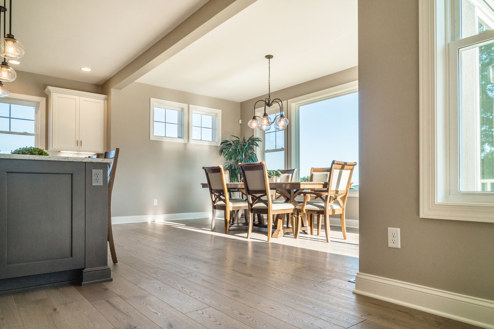 Cette image montre une salle à manger ouverte sur la cuisine minimaliste de taille moyenne avec un mur gris, parquet clair, un sol gris et aucune cheminée.