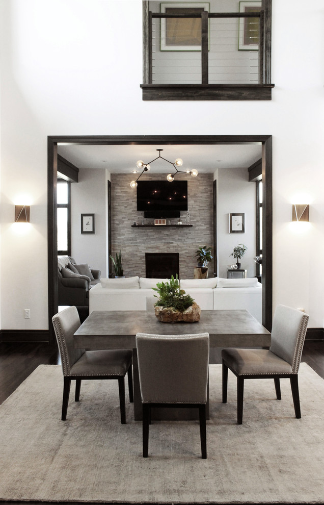 Aménagement d'une salle à manger ouverte sur le salon contemporaine de taille moyenne avec un mur blanc, parquet foncé, une cheminée standard, un manteau de cheminée en pierre et un sol marron.
