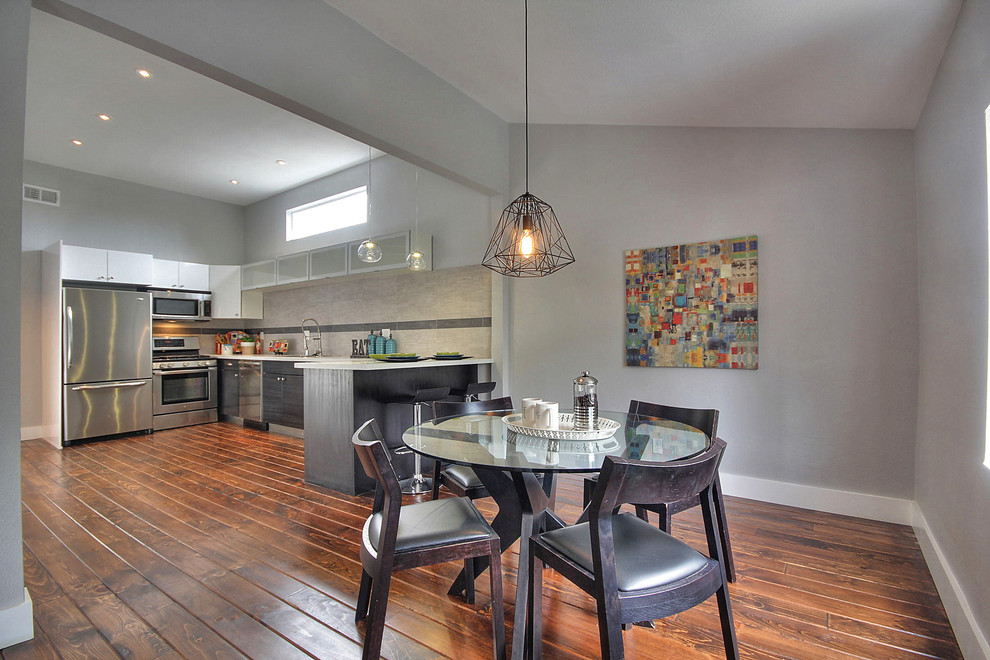 Idée de décoration pour une salle à manger ouverte sur la cuisine tradition avec un mur gris et un sol en bois brun.