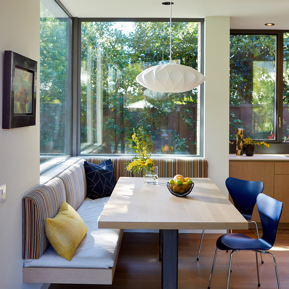 Esempio di una sala da pranzo aperta verso la cucina minimal con pareti bianche, pavimento in legno massello medio e pavimento marrone