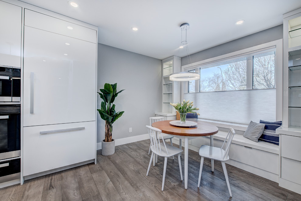 Cette image montre une salle à manger ouverte sur la cuisine design de taille moyenne avec un mur gris, un sol en vinyl, aucune cheminée et un sol gris.