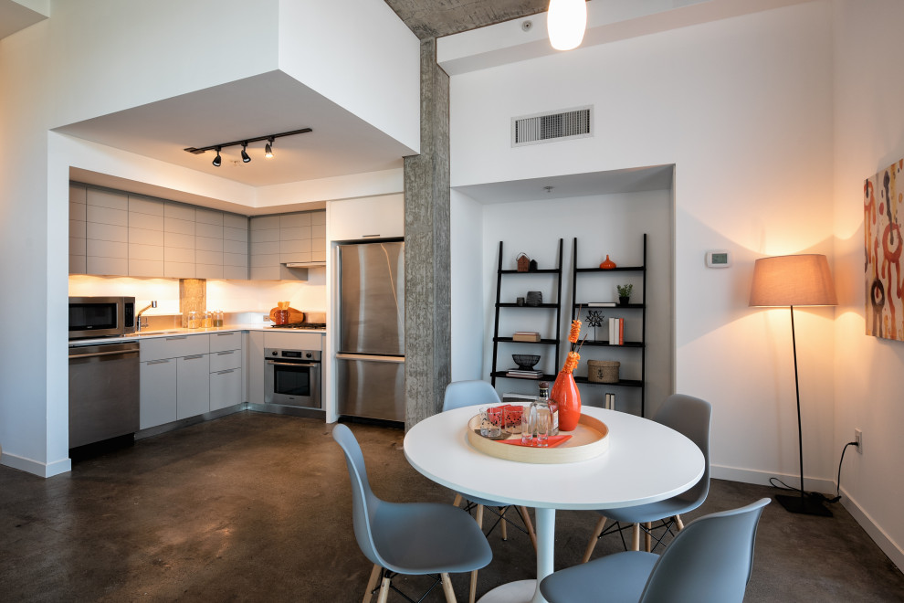 Imagen de comedor de cocina actual pequeño sin chimenea con paredes blancas, suelo de cemento y suelo gris