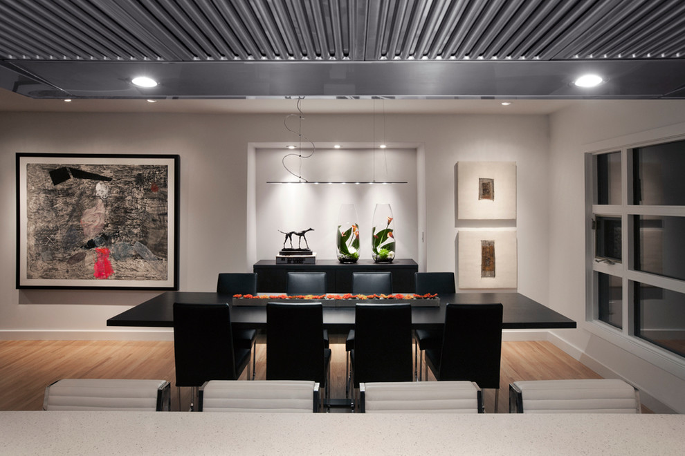 Cette image montre une salle à manger ouverte sur la cuisine design avec un mur blanc, parquet clair et aucune cheminée.