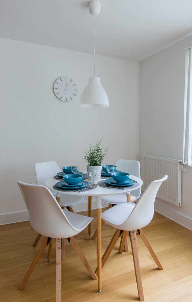 Small scandinavian open plan dining room in Berkshire with white walls, laminate floors and brown floors.