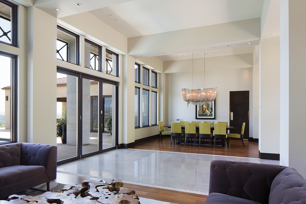 Exemple d'une salle à manger ouverte sur le salon moderne avec un mur blanc et un sol en bois brun.