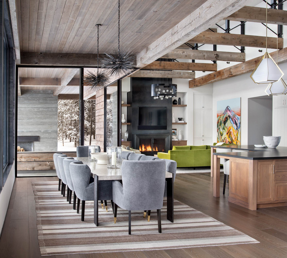 Inspiration pour une salle à manger ouverte sur le salon chalet avec un mur blanc, un sol en bois brun, une cheminée standard, un manteau de cheminée en métal et un plafond en bois.