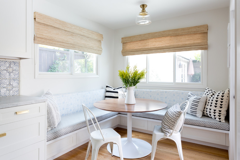 Foto di una sala da pranzo aperta verso il soggiorno stile marinaro con pareti bianche, parquet chiaro e pavimento beige