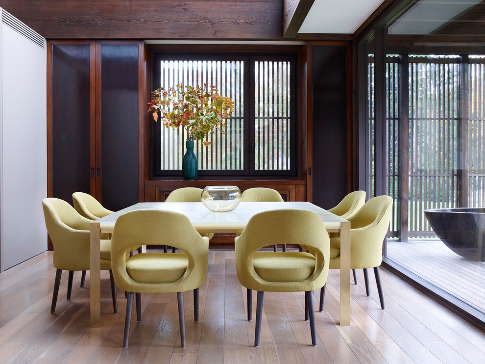 Photo of a world-inspired enclosed dining room in New York with white walls, light hardwood flooring and beige floors.