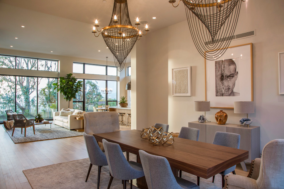 This is an example of a contemporary dining room in Los Angeles with beige walls, medium hardwood flooring and feature lighting.