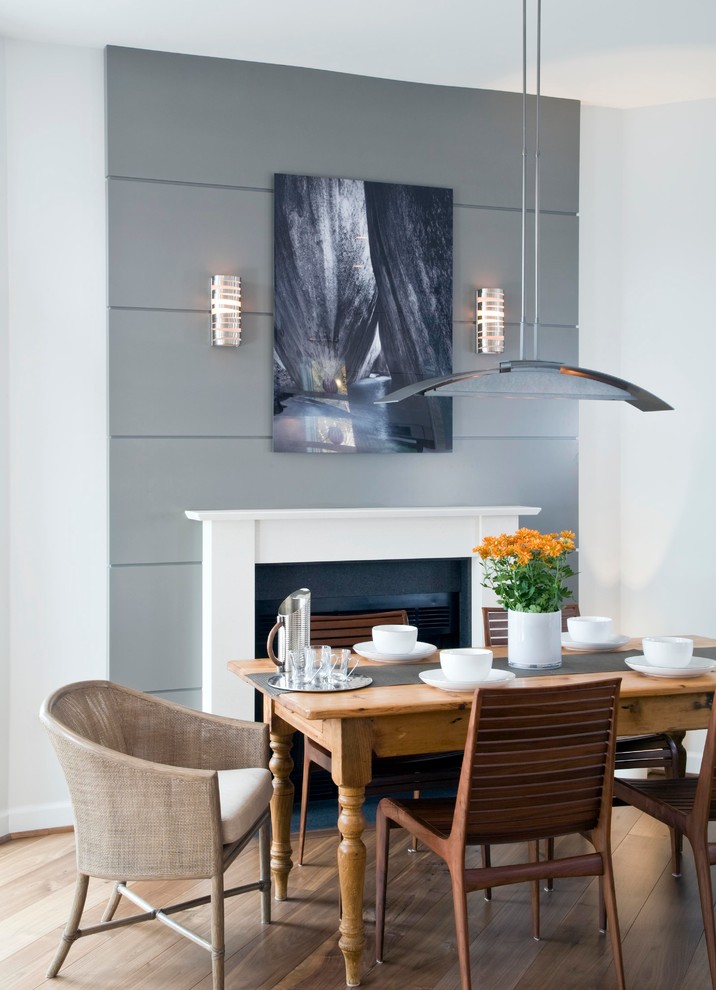 Idées déco pour une salle à manger contemporaine avec un mur gris, un sol en bois brun et une cheminée standard.