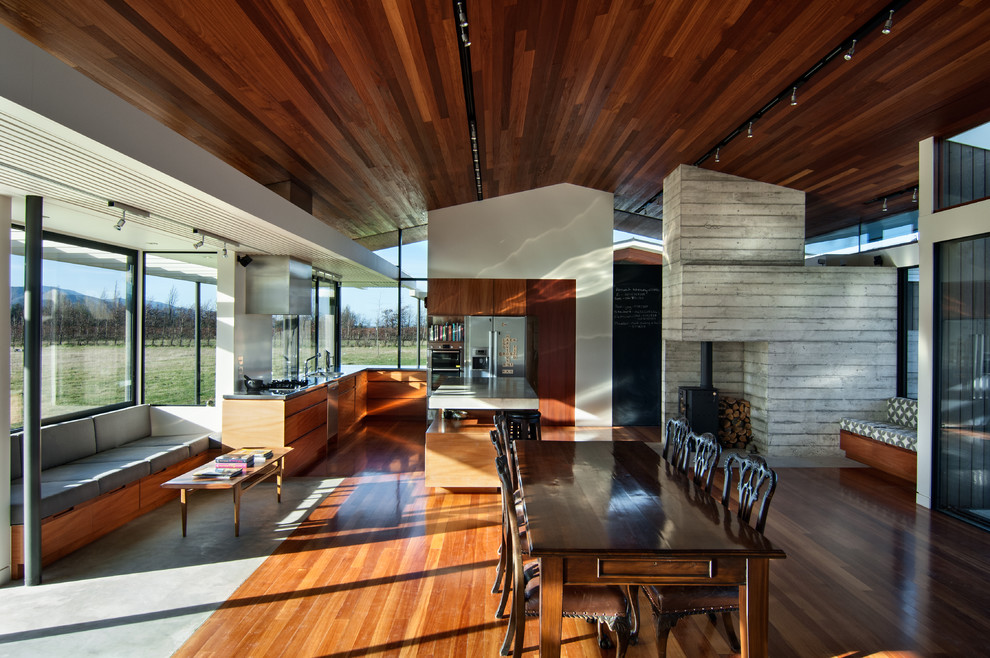 Cette image montre une grande salle à manger ouverte sur la cuisine design avec un sol en bois brun.
