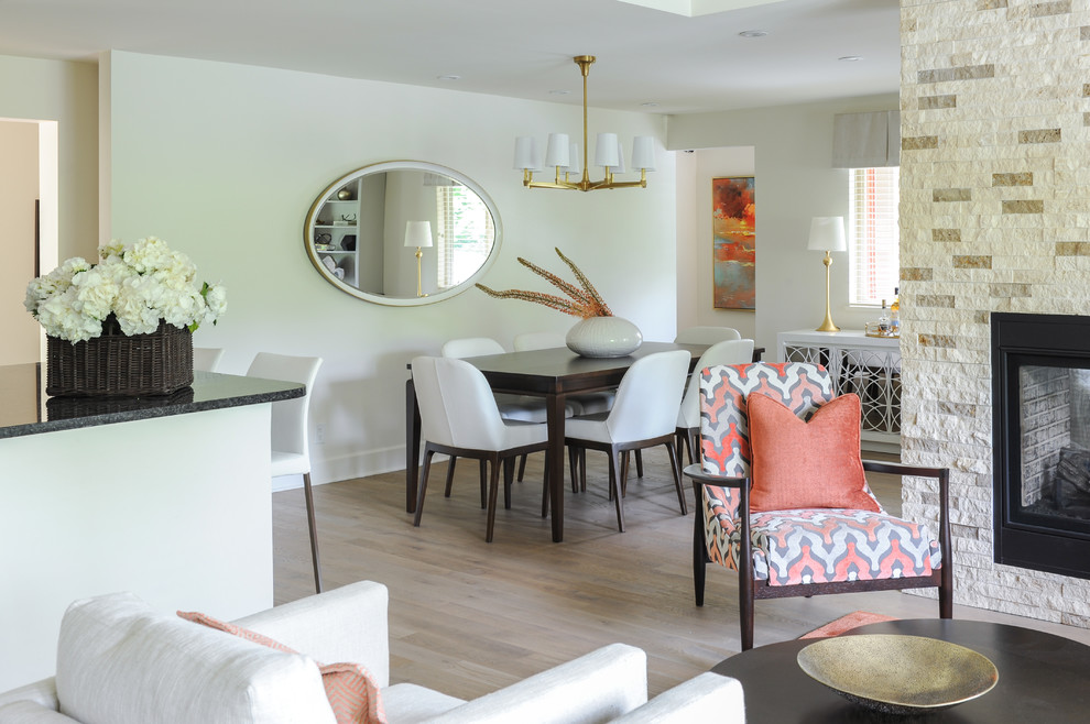 Exemple d'une petite salle à manger ouverte sur le salon chic avec un mur beige, parquet clair, une cheminée double-face, un manteau de cheminée en pierre, un sol marron et éclairage.