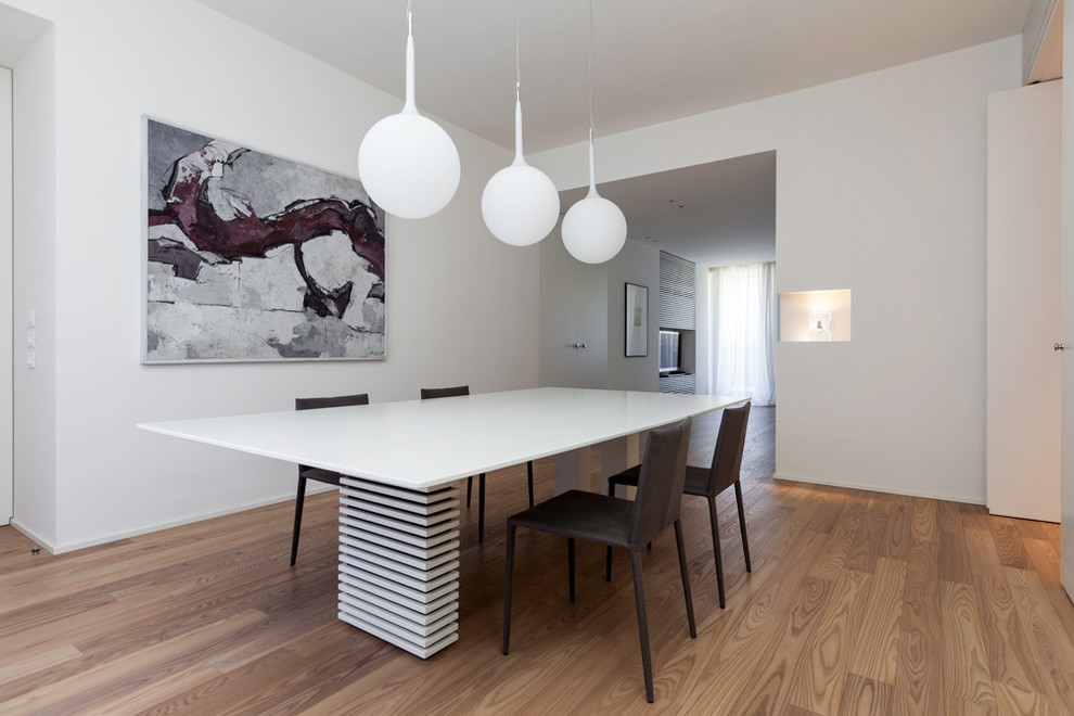 Imagen de comedor moderno abierto con paredes blancas y suelo de madera clara