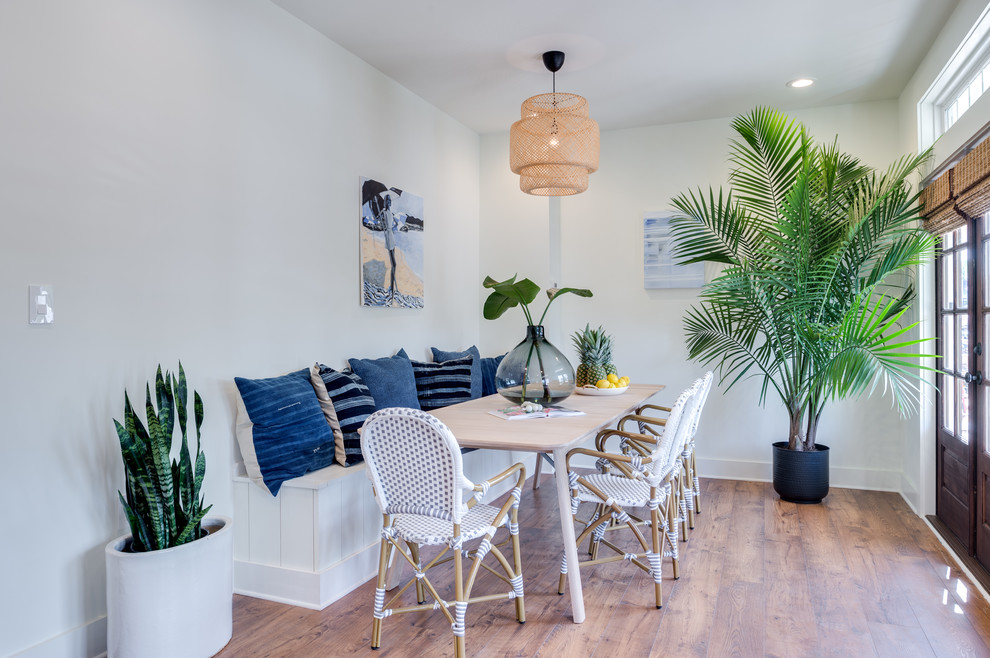 Immagine di una piccola sala da pranzo tropicale chiusa con pareti bianche, pavimento in legno massello medio, nessun camino e pavimento marrone