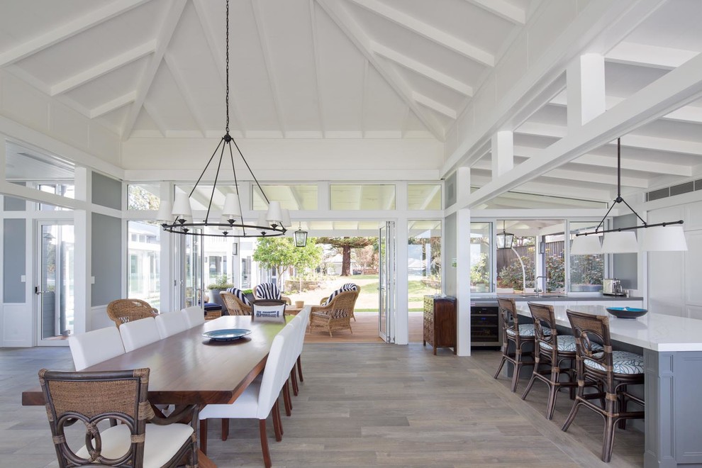 Beach style dining room in Sydney with white walls, medium hardwood flooring, brown floors and feature lighting.