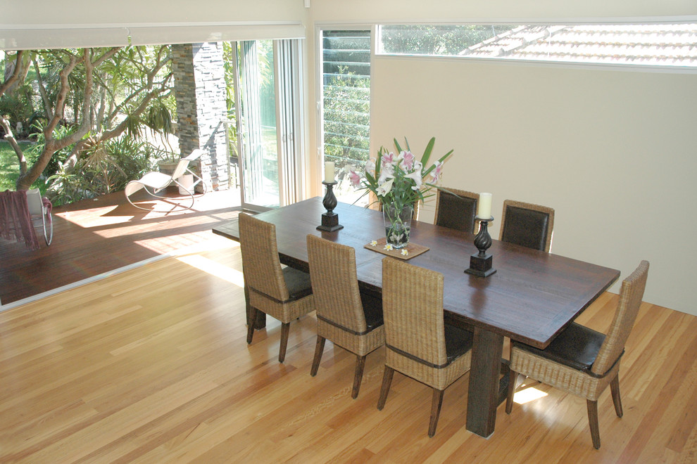 Idée de décoration pour une grande salle à manger ouverte sur le salon design avec un sol en bois brun, une cheminée standard et un manteau de cheminée en pierre.