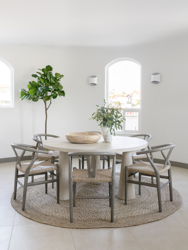 This is an example of a large contemporary dining room in Los Angeles with banquette seating, white walls and beige floors.