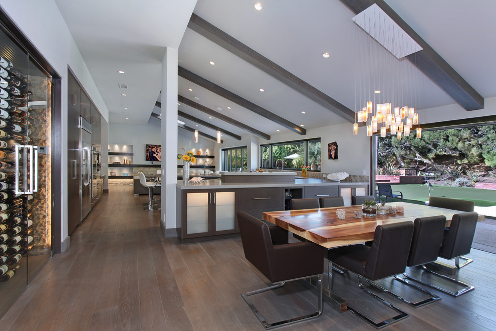 Cette image montre une salle à manger ouverte sur la cuisine design avec un mur blanc et parquet foncé.