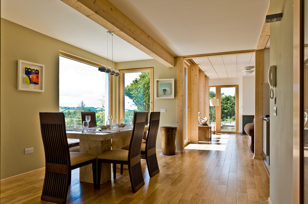 Cette photo montre une salle à manger ouverte sur la cuisine tendance avec un mur vert et un sol en bois brun.