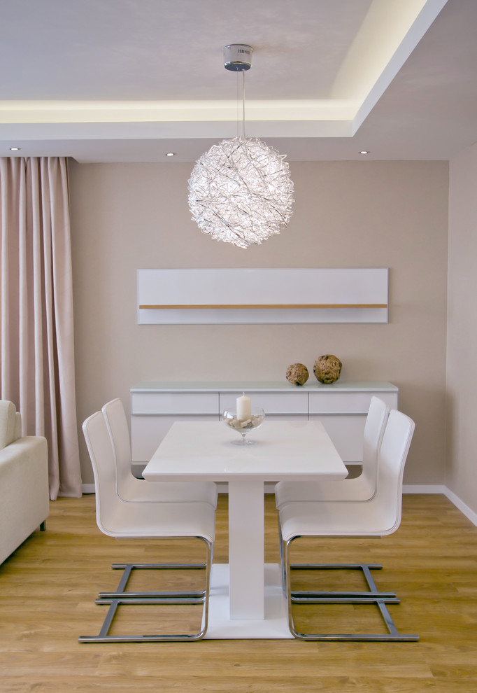 Modernes Esszimmer mit beiger Wandfarbe und braunem Holzboden in Sonstige