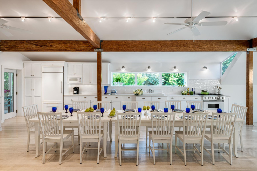 Esempio di un'ampia sala da pranzo aperta verso la cucina costiera con pareti bianche e parquet chiaro