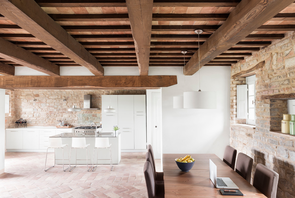 Foto di una grande sala da pranzo aperta verso il soggiorno mediterranea con pareti bianche e pavimento in mattoni