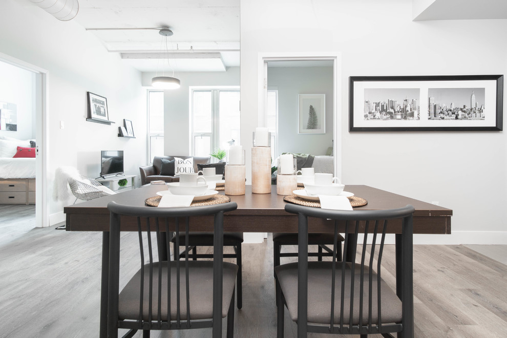 Cette image montre une salle à manger ouverte sur la cuisine design de taille moyenne avec un mur blanc, sol en stratifié et un sol gris.