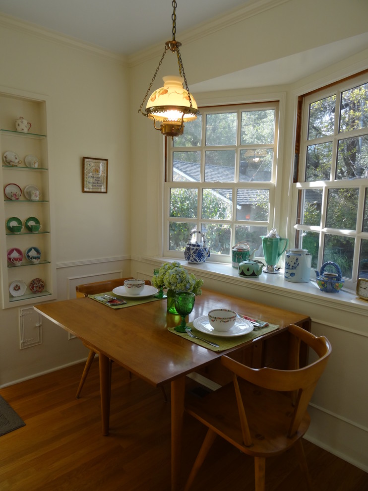 Immagine di una piccola sala da pranzo aperta verso la cucina country con pareti gialle, pavimento in legno massello medio e nessun camino