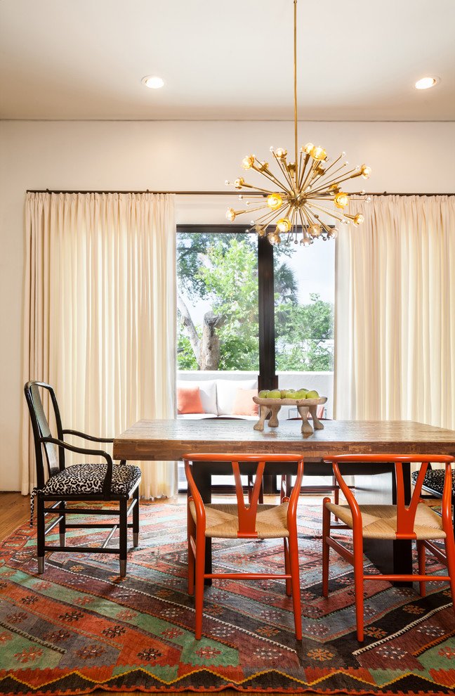This is an example of a bohemian dining room in Houston with white walls and medium hardwood flooring.