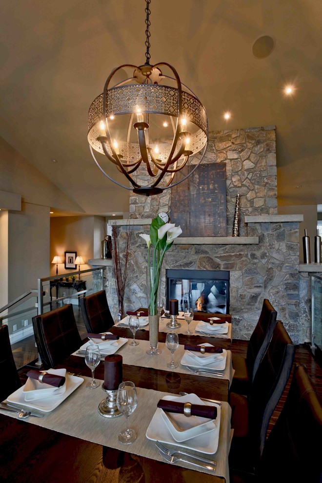 Foto di una sala da pranzo aperta verso la cucina tradizionale con pareti beige, pavimento in legno massello medio, camino bifacciale e cornice del camino in pietra