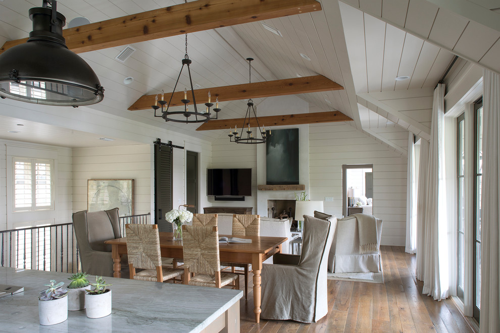 Foto di una sala da pranzo aperta verso il soggiorno stile marino con pareti bianche, pavimento in legno massello medio e pavimento marrone