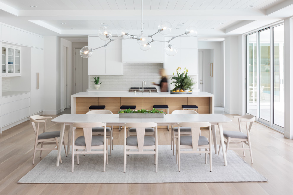 Aménagement d'une salle à manger ouverte sur le salon bord de mer avec un mur blanc, parquet clair et un sol beige.