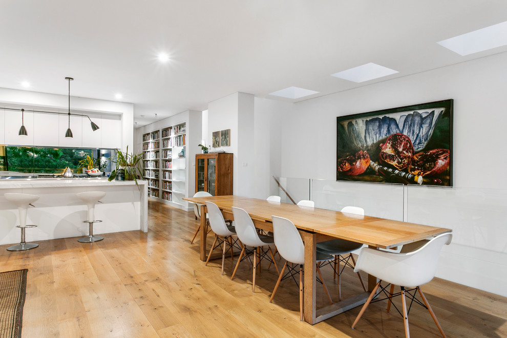 Immagine di una sala da pranzo aperta verso il soggiorno minimal di medie dimensioni con pareti bianche, parquet chiaro e pavimento beige