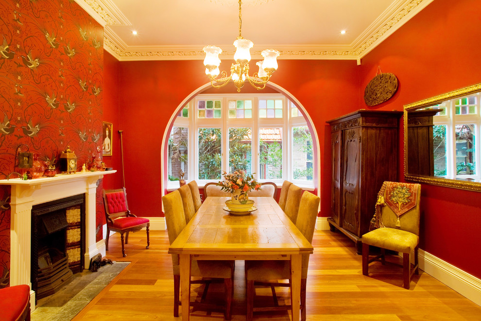 Immagine di una sala da pranzo classica con pareti rosse e camino classico