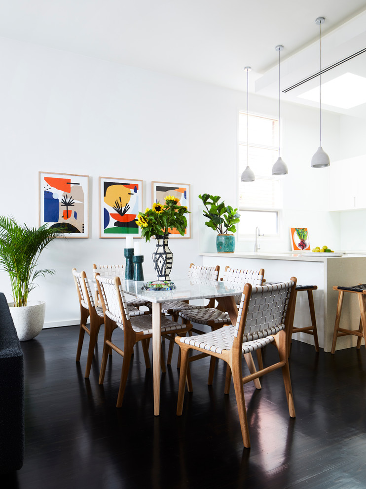 Foto di una sala da pranzo aperta verso il soggiorno minimal con pareti bianche, pavimento in legno verniciato e pavimento nero