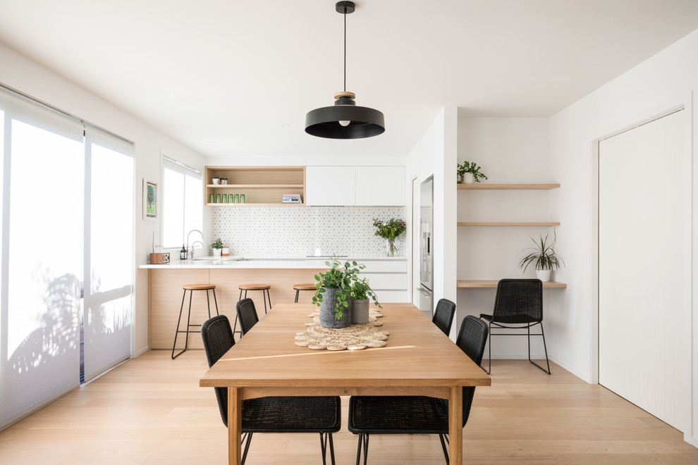 Cette image montre une petite salle à manger ouverte sur la cuisine marine avec parquet clair, un mur blanc et un sol beige.