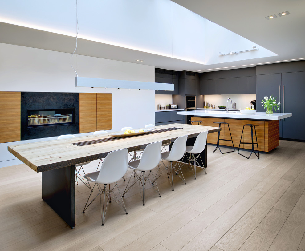 Стильный дизайн: кухня-столовая в скандинавском стиле с белыми стенами, светлым паркетным полом, горизонтальным камином и фасадом камина из металла - последний тренд