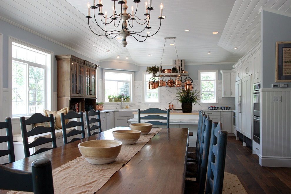 Foto di una sala da pranzo aperta verso la cucina country con pareti blu e pavimento in legno massello medio