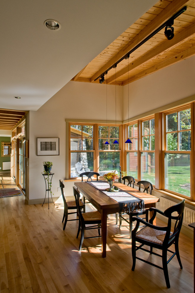 Inspiration pour une salle à manger ouverte sur le salon craftsman de taille moyenne avec un mur blanc, parquet clair, aucune cheminée, un sol marron et éclairage.